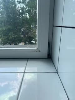 Dolny narożnik dużego okna PCV z widocznym zaczepem okucia przed wymianą.