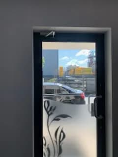 Antracytowe drzwi aluminiowe z samozamykaczem nad skrzydłem przed regulacją domykania.