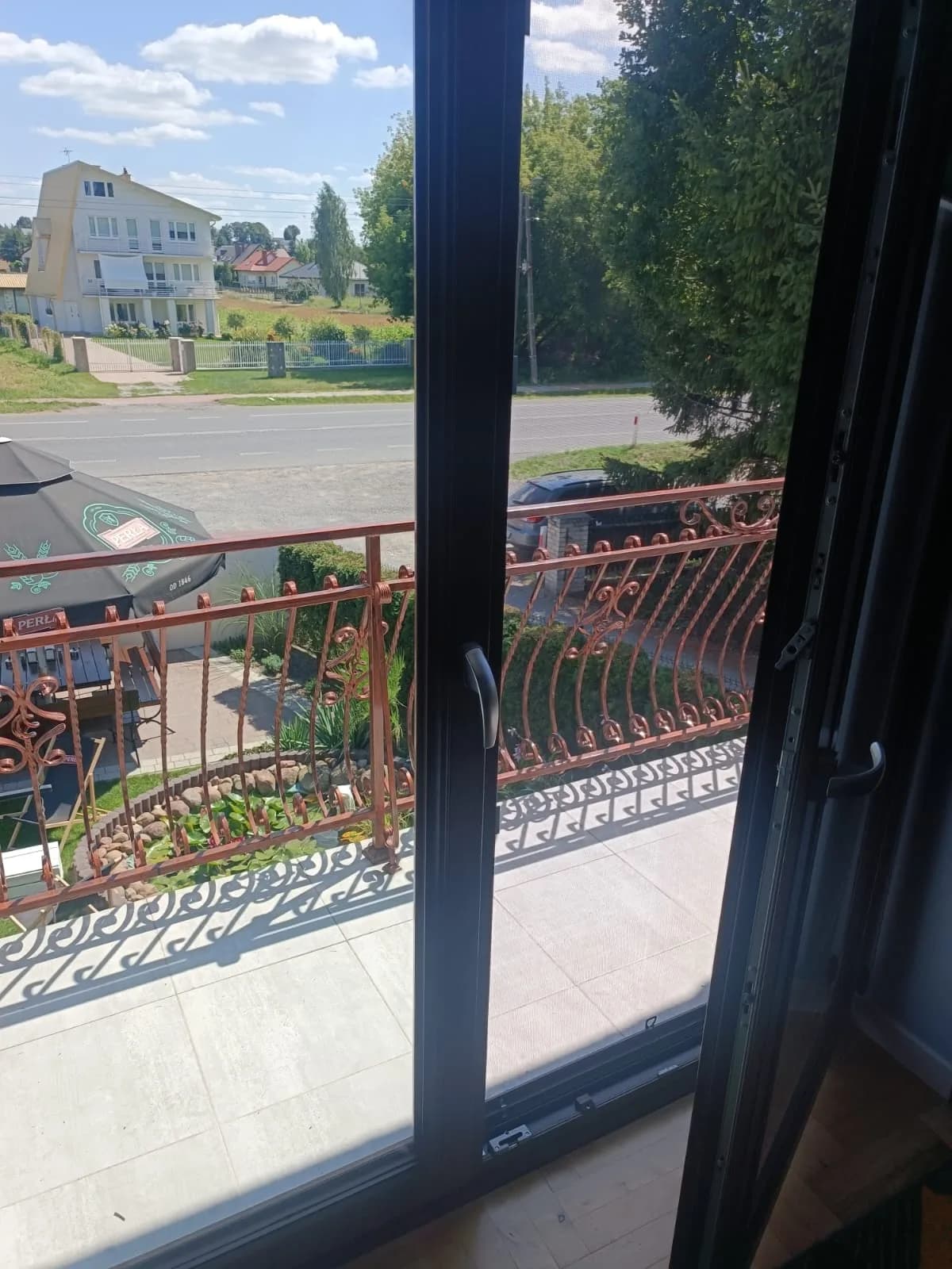 Brązowe drzwi balkonowe po wymianie uszczelek, otwarte skrzydło i widoczne okucia.