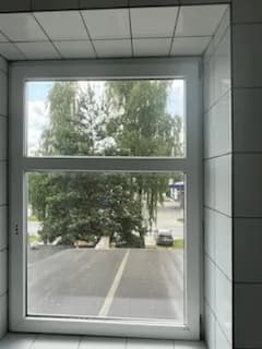 Duże białe okno PCV z górnym naświetlem w pomieszczeniu wyłożonym płytkami, przy wymianie okuć.
