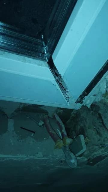 Pęknięty dolny narożnik skrzydła okna PCV nad skutym tynkiem ościeżnicy.