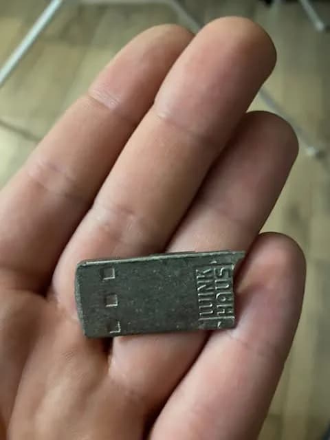 Pęknięty metalowy element kasetki okiennej trzymany w dłoni po wyjęciu z okucia.