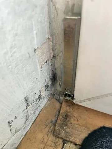 Metalowa płyta zawiasu osadzona w ościeżnicy białego okna PCV po naprawie mocowania.
