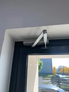 Samozamykacz z ramieniem nad antracytowymi drzwiami aluminiowymi po ustawieniu siły domykania.