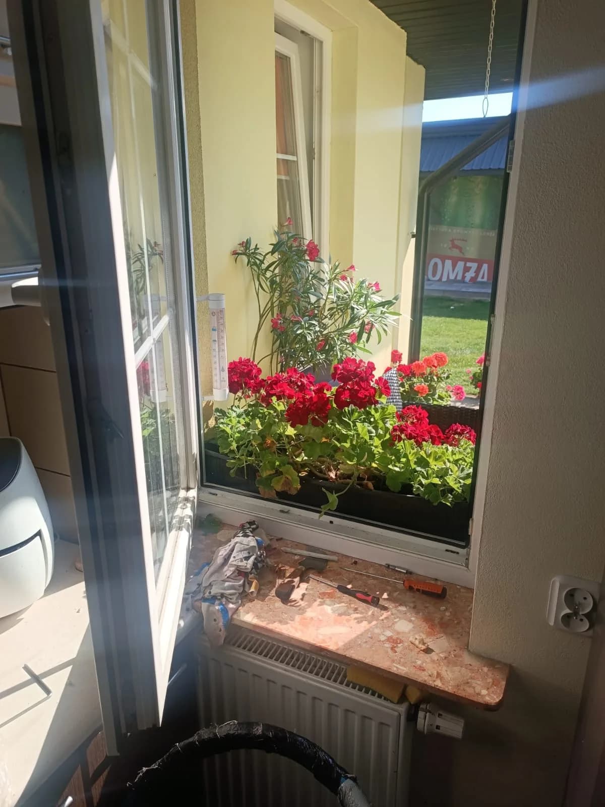 Otwarte okno PVC po wymianie uszczelek, na parapecie pozostały narzędzia i drobne odcinki uszczelki.