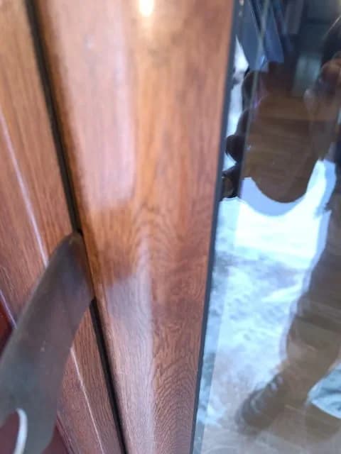 Widoczna szczelina między skrzydłem a ościeżnicą brązowych drzwi balkonowych.