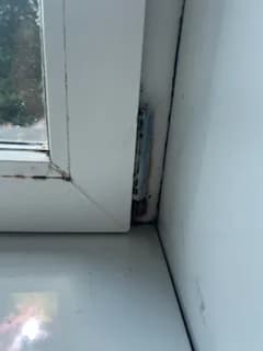 Zabrudzony zaczep okucia w ościeżnicy białego okna PCV przed wymianą okuć.