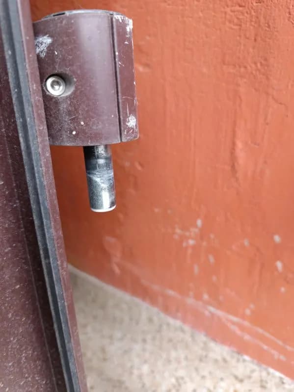 Zawias brązowych drzwi aluminiowych z wysuniętym trzpieniem podczas regulacji.